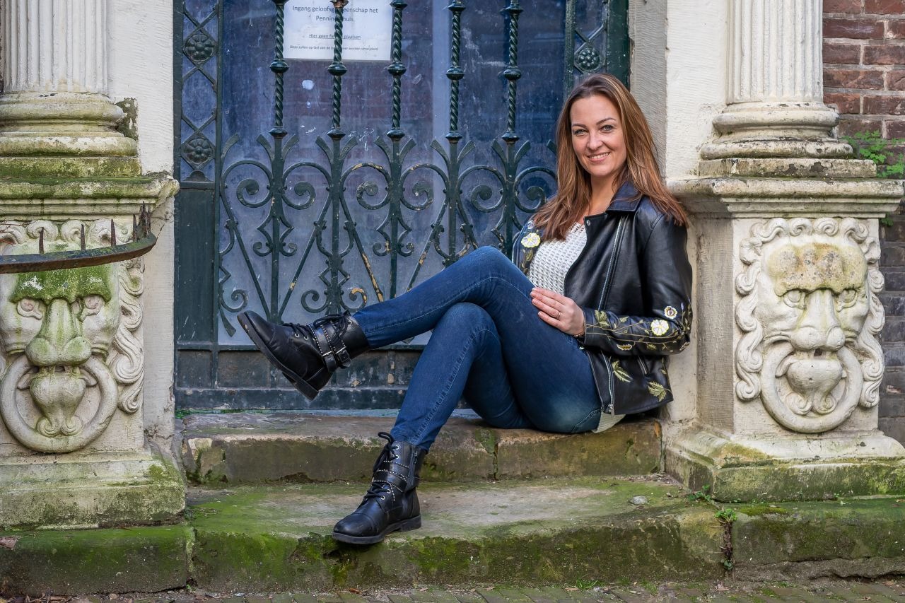 Marieke Koene zittend op stoep voor smeedijzeren hek